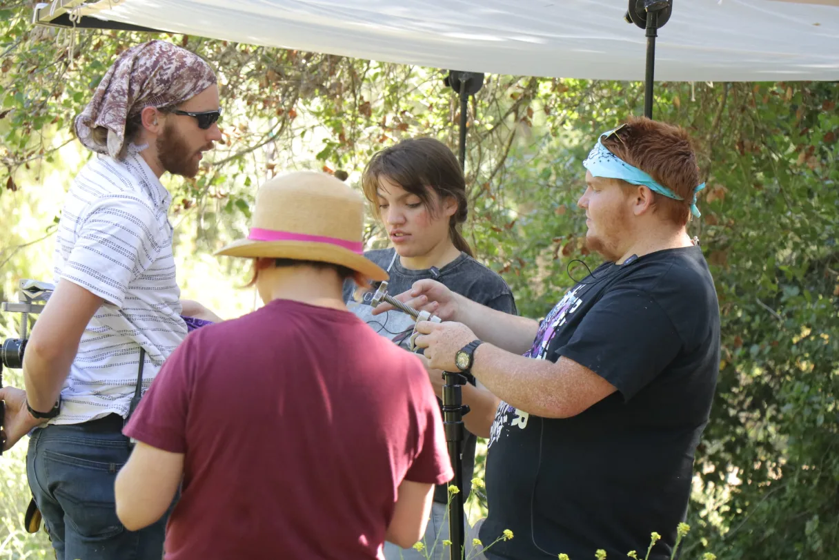 Emergency Pineapple Studios crew rigging equipment outdoors under a canopy on a sunny production day